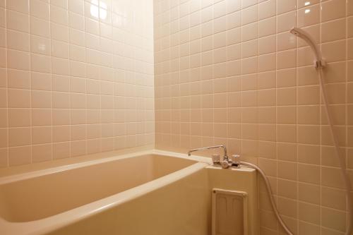 a bath tub in a bathroom with white tiles at Hanagoyomi in Sumoto
