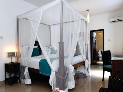 a bedroom with a canopy bed with white curtains at Maru Maru Hotel in Zanzibar City