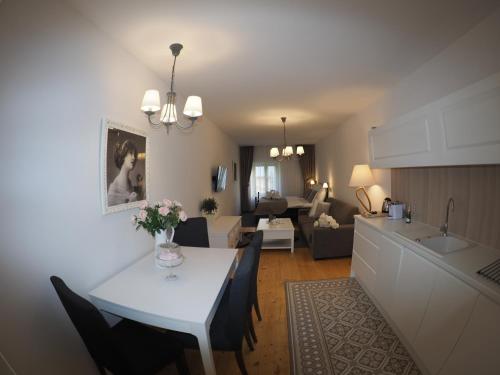 a kitchen and living room with a white table and chairs at Wise Owl Apartments in Banská Štiavnica
