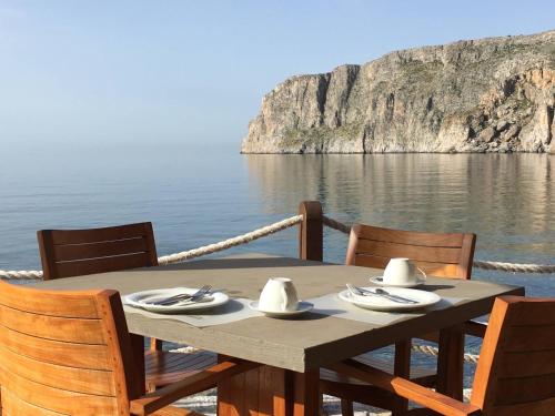 a wooden table with chairs and a view of the water at Kyrimai Hotel in Gerolimenas