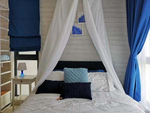1 dormitorio con cama con dosel y cortinas azules en H2O Residences Marine Blue by ADDS, en Petaling Jaya