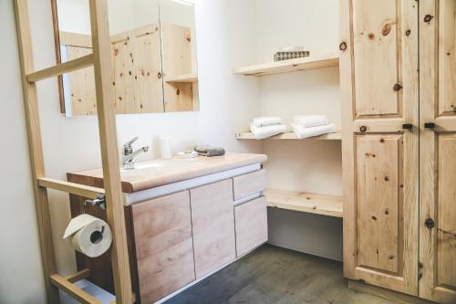 ein Badezimmer mit einem Waschbecken und Holzschränken in der Unterkunft Il Maschun im historischen Engadinerhaus in Scuol