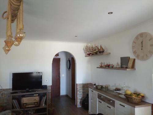 a living room with a tv and a clock on the wall at Abrigo das Nortadas in Vila do Bispo