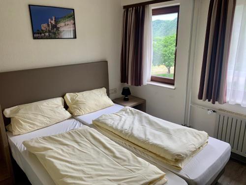 a bedroom with two beds with white sheets and a window at Hotel Montag in Sankt Goar
