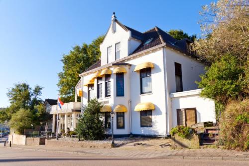 une maison blanche avec des auvents jaunes dans une rue dans l'établissement Mare Sanat, à Wijk aan Zee