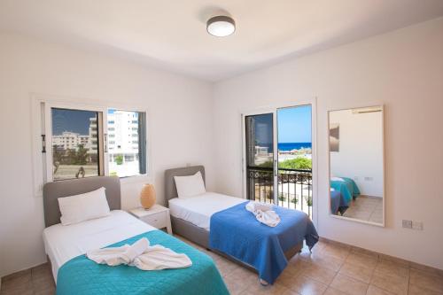 a bedroom with two beds and a balcony at Jason Villas in Protaras