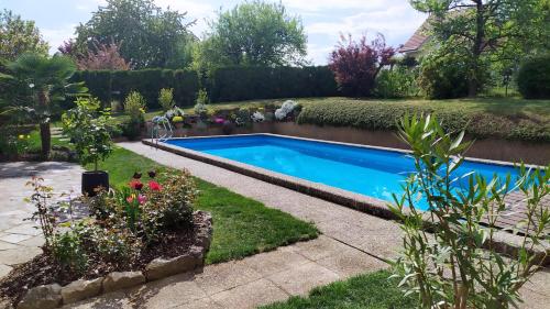 a swimming pool in a garden with flowers at Guest House La Sereine in Romanel-sur-Lausanne