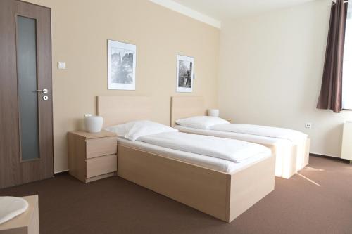 2 Betten in einem weißen Zimmer mit in der Unterkunft Penzion Švýcarský dům in Sněžnik
