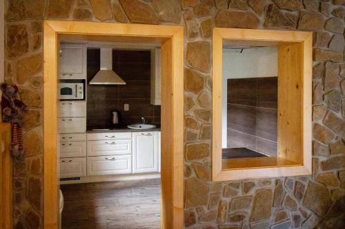 a kitchen with a stone wall and a mirror at Chata Lienka in Lazisko