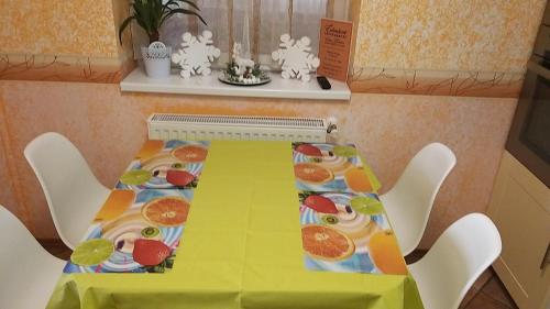 a yellow table with fruit on it with white chairs at Édenkert Apartmanház in Kisvárda