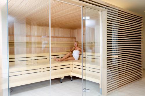 a woman is sitting in a sauna at Hotel Stoiser in Loipersdorf bei Fürstenfeld