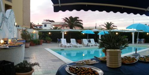 een tafel met eten naast een zwembad bij Hotel Lido Garda in Anzio