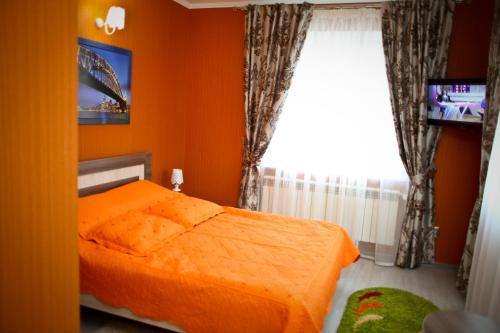 1 dormitorio con cama de color naranja y ventana en Dalos Plus en Sarny