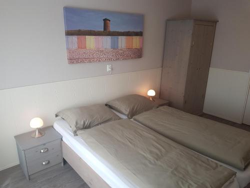 een slaapkamer met een bed en een schilderij aan de muur bij Appartement met inpandig balkon, 150 meter verwijderd van strand en centrum in Zoutelande