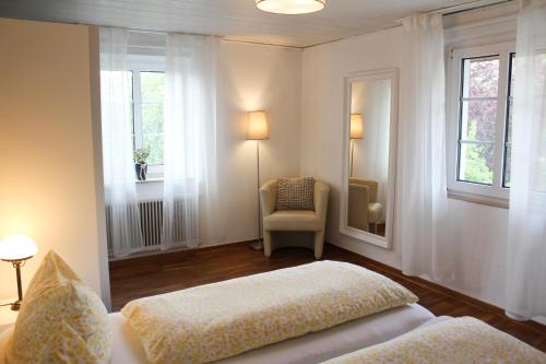 Ferienwohnung am Stemberg في ديتمولد: غرفة نوم بسرير وكرسي ونوافذ