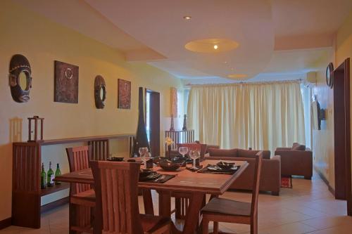 a dining room with a table and a living room at Cowrie Shell Beach Apartments Official in Bamburi