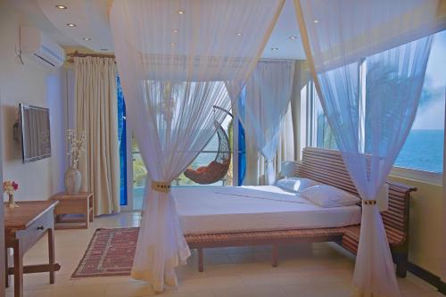 a bedroom with a canopy bed with a view of the ocean at Cowrie Shell Beach Apartments Official in Bamburi