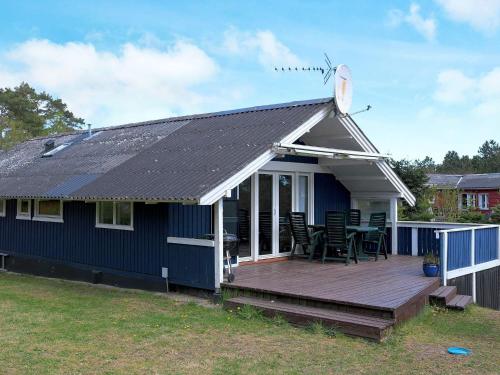 una casa azul con una terraza y sillas. en 6 person holiday home in Hadsund, en Als