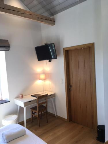 Schlafzimmer mit einem Schreibtisch und einem TV an der Wand in der Unterkunft B&B Pegasus II - Chambre de luxe avec sauna privatif in Vielsalm