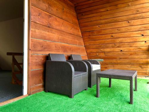 two chairs and a stool in a room with wooden walls at Wigierska Osada 2 in Danowskie