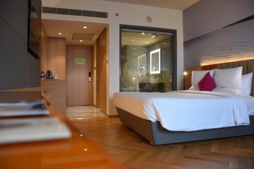 a bedroom with a large white bed with red pillows at Novotel Vijayawada Varun in Vijayawāda