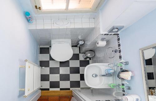 a bathroom with a toilet and a checkered wall at Loreta Hotel in Prague