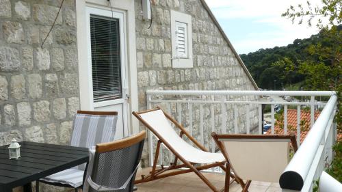 a balcony with chairs and a table and a building at Eco Apartments Kate in Suđurađ