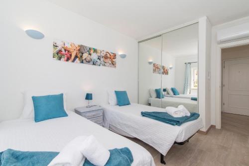 a bedroom with two beds and a mirror at Casa dos Peixes in Armação de Pêra