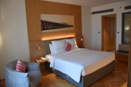 a hotel room with a large bed and a chair at Novotel Vijayawada Varun in Vijayawāda