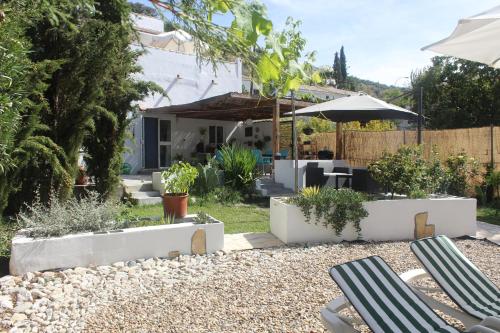 a backyard with two lawn chairs and an umbrella at Casa La Nuez in Almedinilla