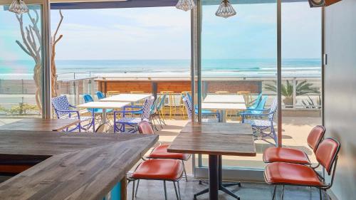 a restaurant with tables and chairs and the beach at zaimokuza seasons in Kamakura