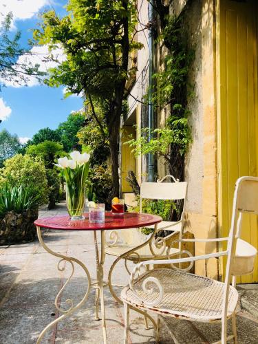 a table and chairs on a patio with a vase of flowers at Hôtel Le Cro-Magnon in Les Eyzies-de-Tayac