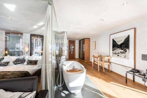 a large bathroom with a tub and a bedroom at Matterhorn FOCUS Design Hotel in Zermatt
