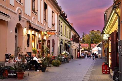 a city street with people sitting at tables and buildings at Afrodité Apartmanok in Eger