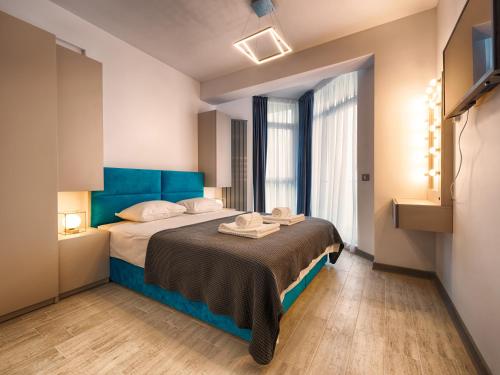 une chambre avec un grand lit et une tête de lit bleue dans l'établissement Sunway - Pool & Spa Beach Resort, à Mamaia Nord – Năvodari