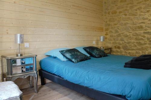 a bedroom with a blue bed with a wooden wall at chambres d’hôte le breuil in Sarlat-la-Canéda