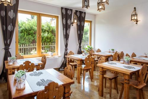 un restaurante con mesas y sillas de madera y ventanas en Dom Wypoczynkowy Koliba, en Białka Tatrzanska