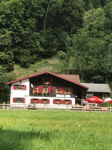 a red and white building with a field in front of it at Gasthaus Pension Montafonerhüsli in Sankt Gallenkirch