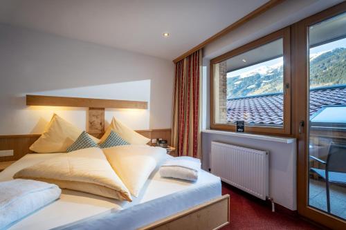 a bedroom with a bed and a large window at Alpenhof Hotel Garni Suprême in Zell am Ziller