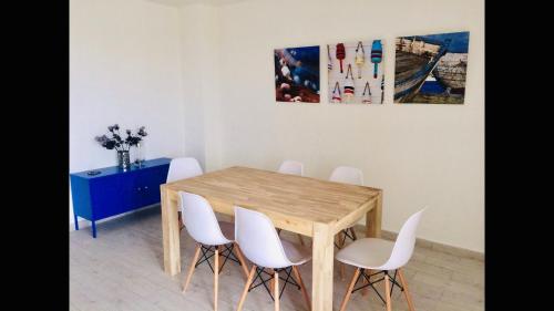 une salle à manger avec une table en bois et des chaises blanches dans l'établissement Appartement vue mer, rivière et montagnes, à Sari-Solenzara