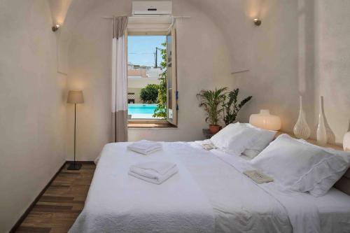 sypialnia z dużym białym łóżkiem i oknem w obiekcie Sandandstone villa Santorini w mieście Megalochori