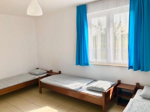 a room with two beds and a window with blue curtains at Azymut in Władysławowo