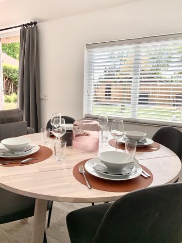 a dining room table with plates and wine glasses at Liv Residence Holiday Home with Sauna & Fireplace in Ermelo