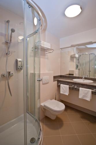 a bathroom with a shower and a toilet and a sink at Hotel Croatia in Zagreb