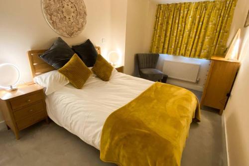a bedroom with a bed with a yellow blanket on it at 13 The Grosvenor, luxury flat, central Newmarket, in Newmarket