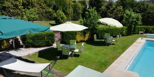 un patio trasero con piscina, sillas y sombrillas en My Portugal for All - Lousada Villa en Lousada