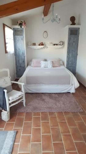 a bedroom with a large white bed and a chair at Chambre d'hôtes l'ipomée in Gémenos