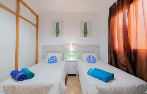 2 Betten in einem Zimmer mit 2 blauen Kissen in der Unterkunft THREE BEDROOM APARTAMENT NEAR SANTA CRUz 1A in Santa Cruz de Tenerife