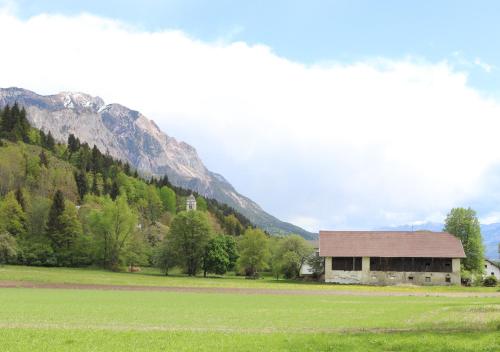 a building in a field next to a mountain at Pension Leano in Nötsch