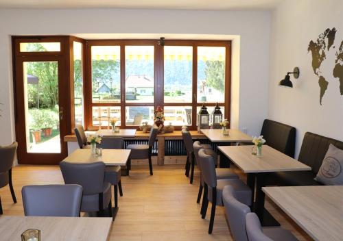 een restaurant met houten tafels, stoelen en ramen bij Pension Leano in Nötsch